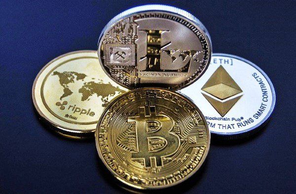 A collection of physical representations of cryptocurrencies like Bitcoin, Ripple, Ethereum, and Litecoin.