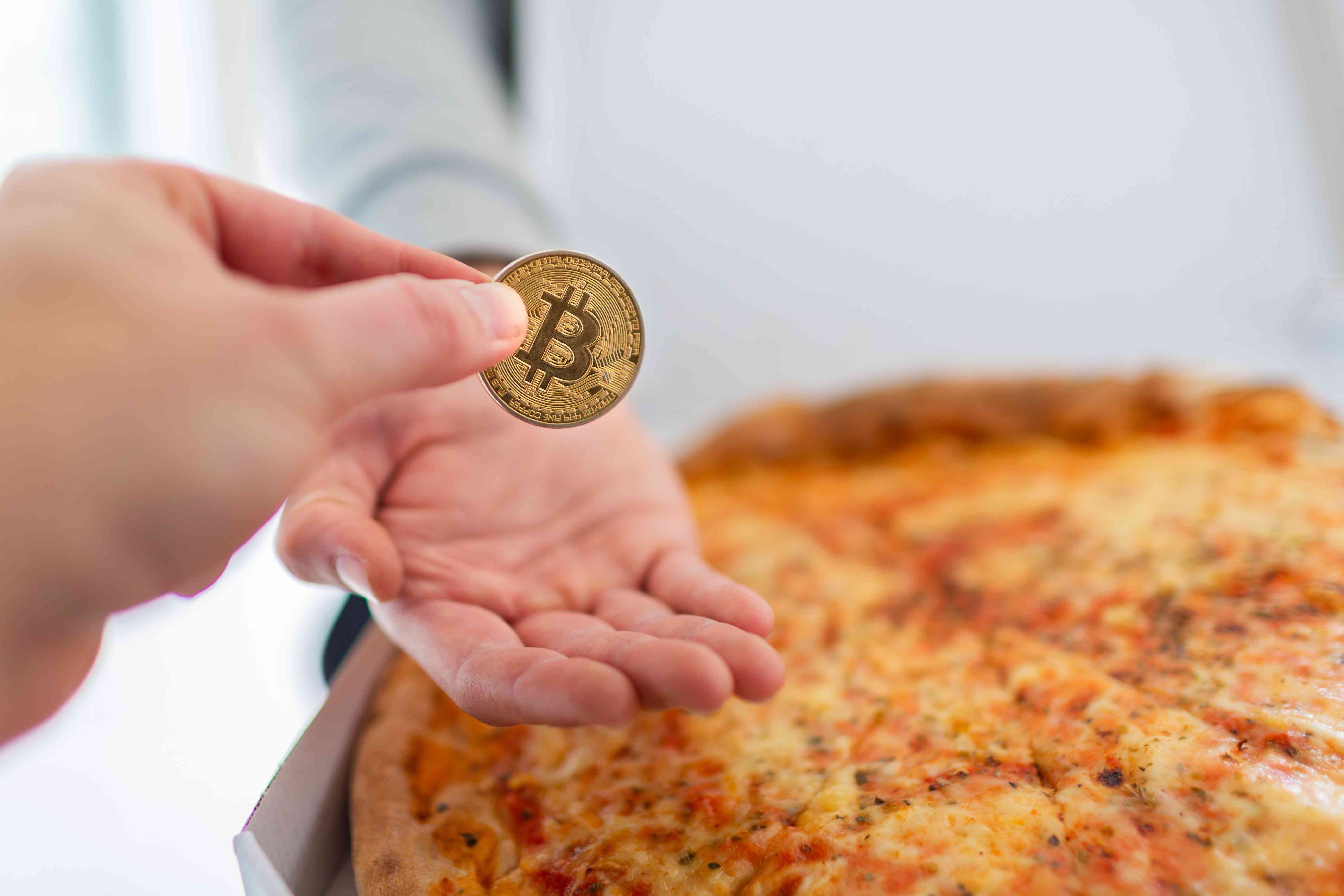Handing over a bitcoin for a pizza