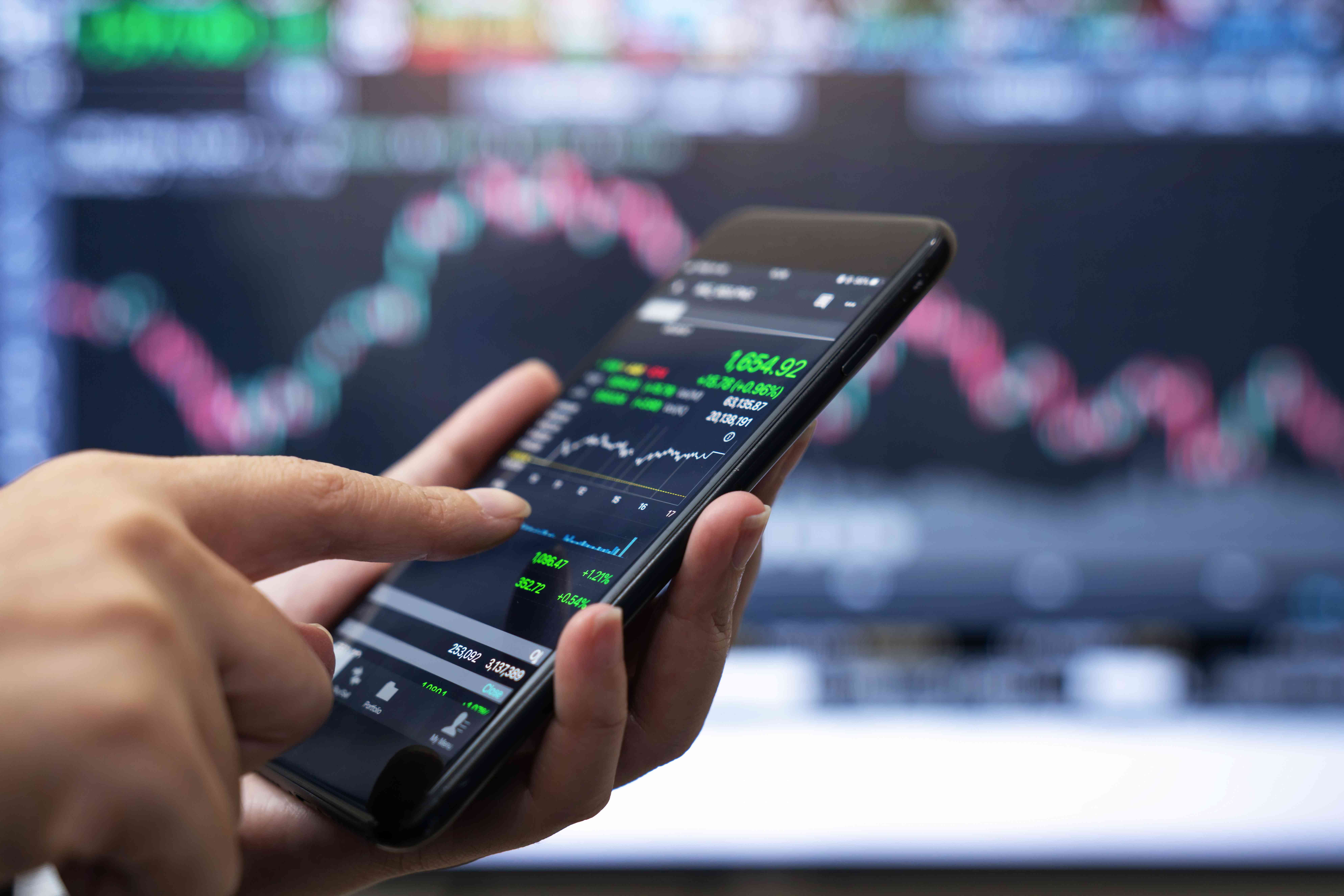 A person holds a smart phone depicting a stock chart