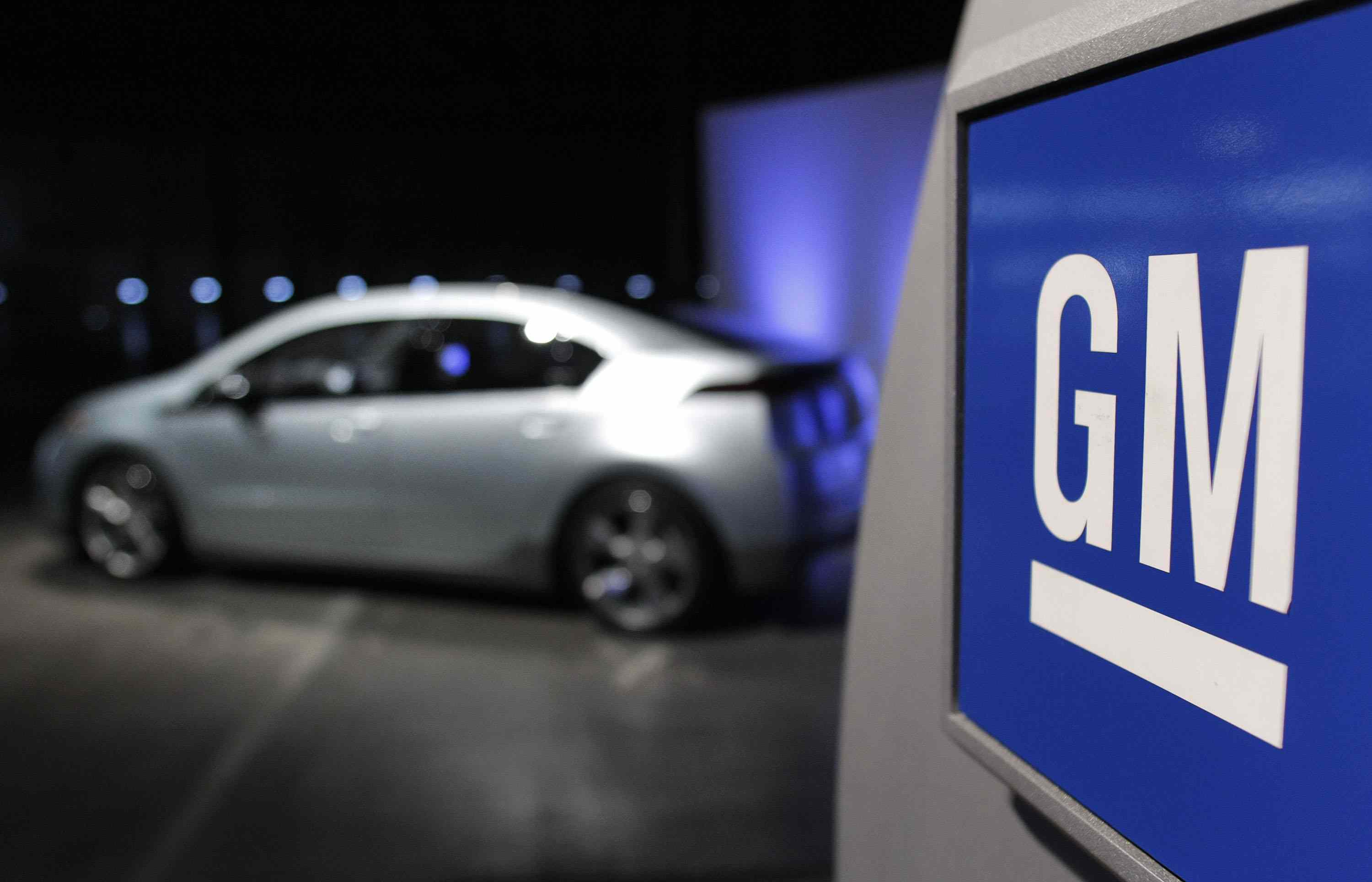 A Chevrolet Volt electric vehicle is on display beside a GM sign